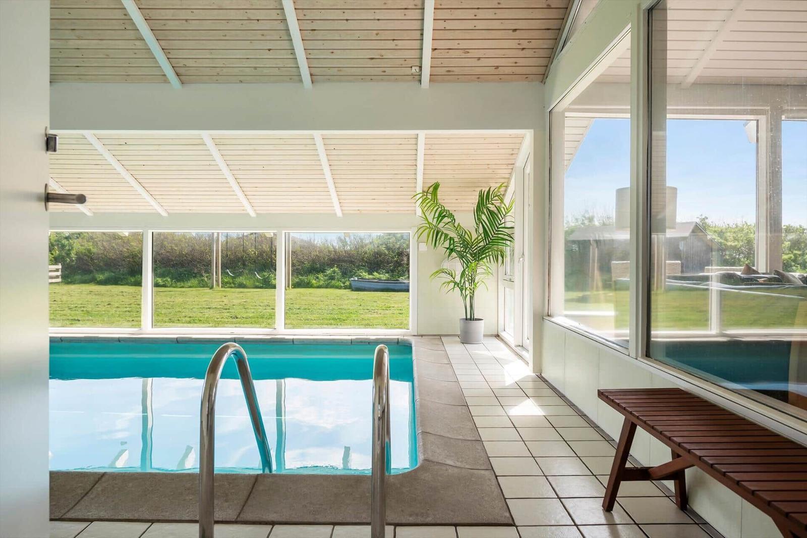 Indoor pool with wooden ceiling and large windows to the garden