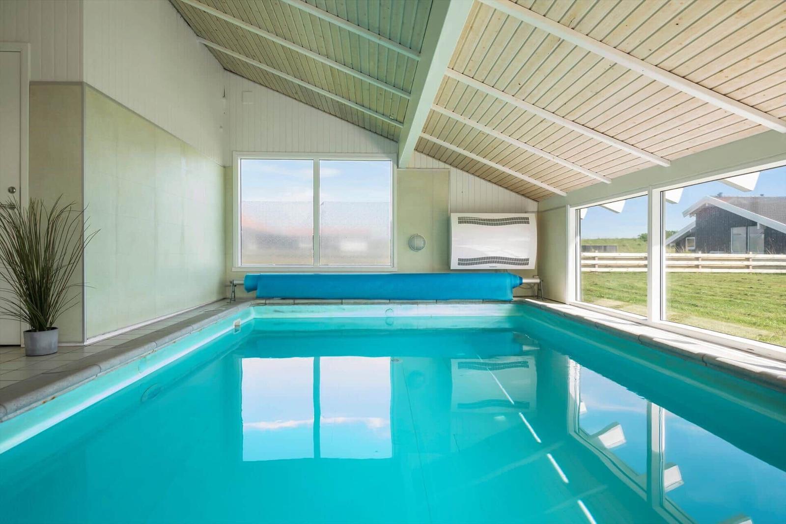 Indoor pool with blue water and large windows for views.