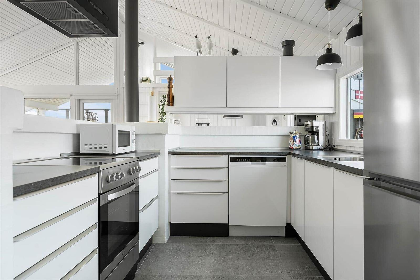 Modern kitchen with white cabinets, stainless steel appliances, and dark worktops.