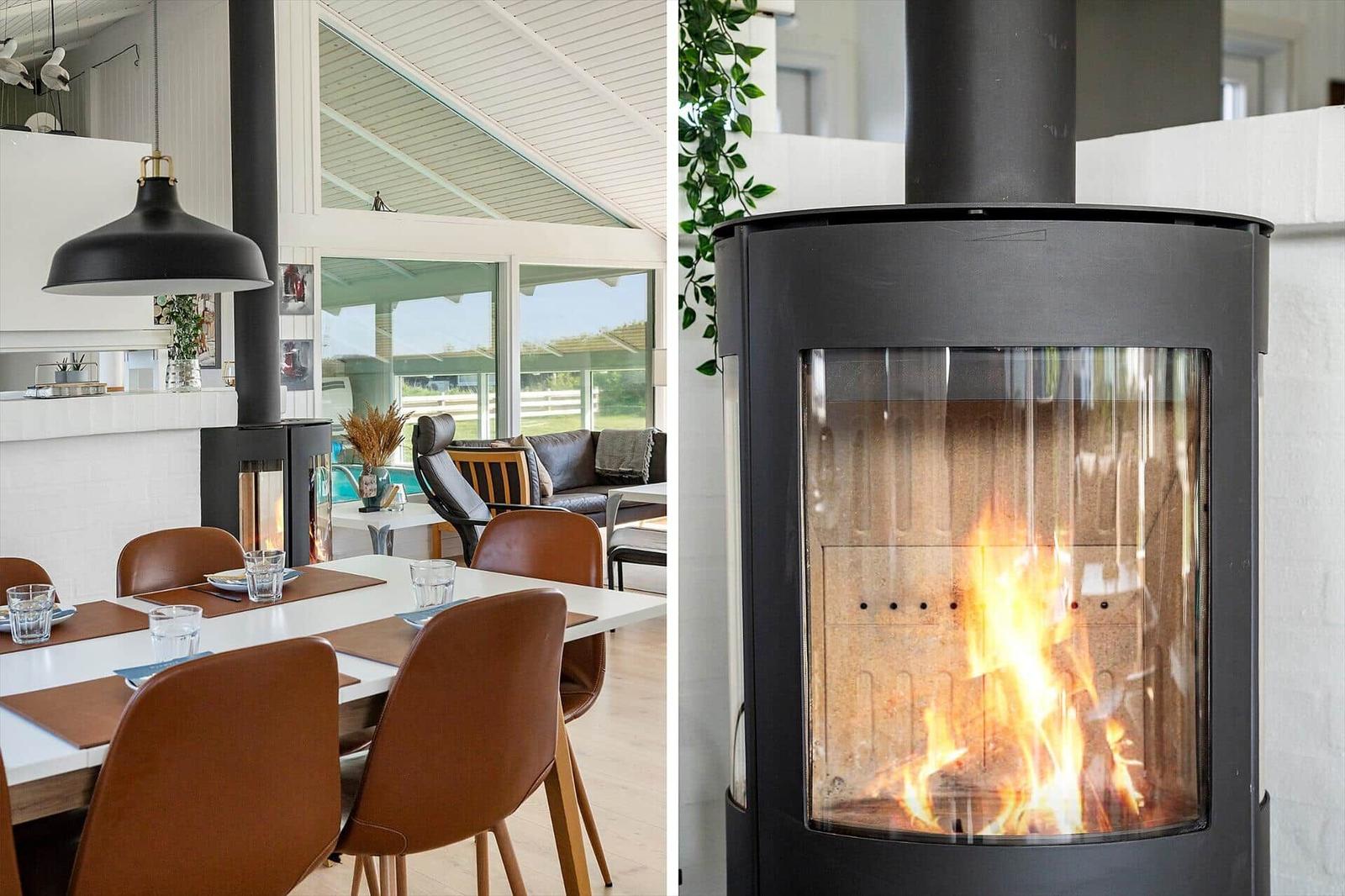 Dining area with table and chairs, wood-burning stove with fire in the background.