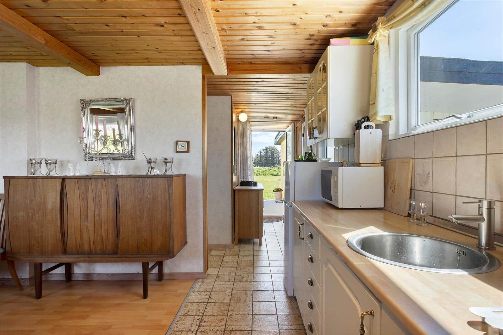 Kitchen with worktop, sink, and kitchen cabinets. Wooden ceiling and sideboard in background.