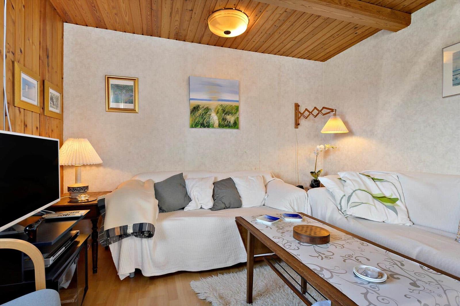 Living room with sofa, coffee table, and TV under wooden ceiling.