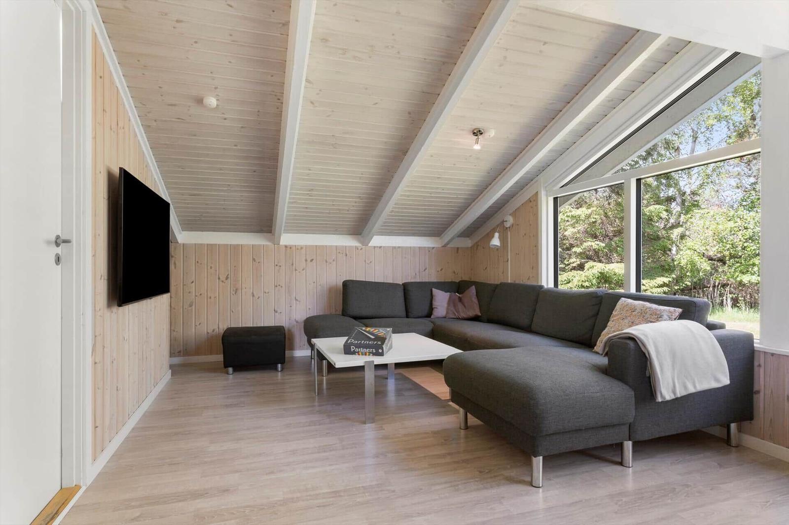 Living room with gray sofa, TV, and large window to nature.