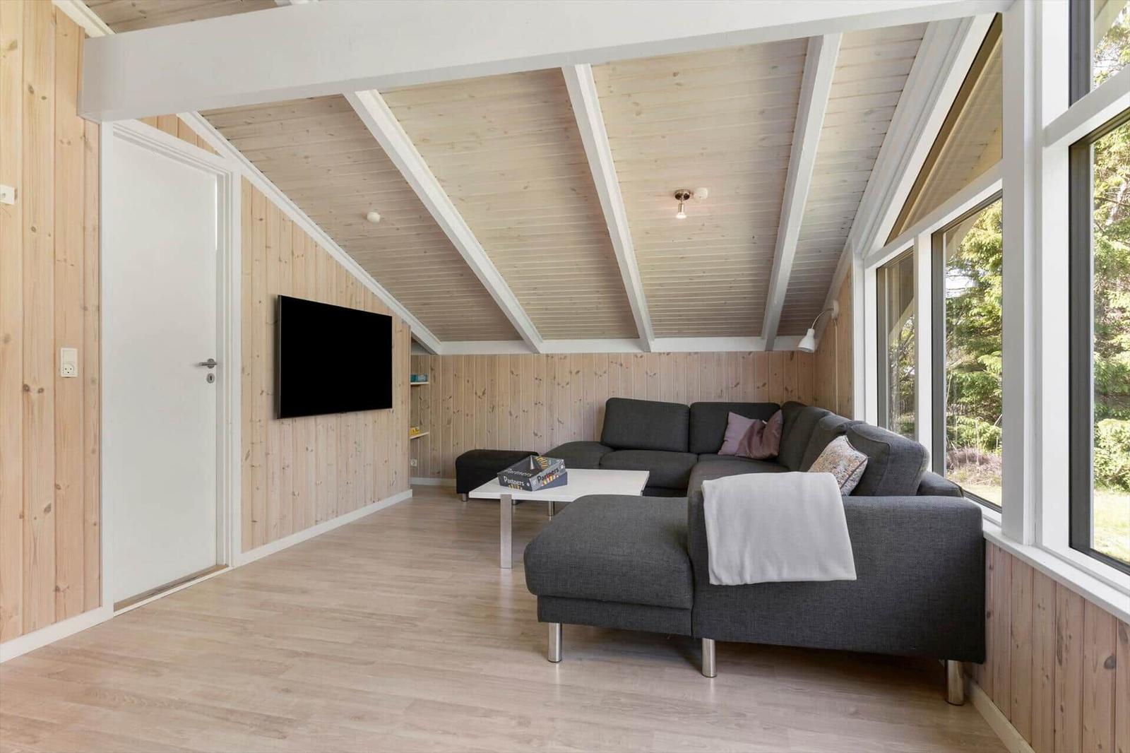 Living room with gray sofa, TV, and large windows.