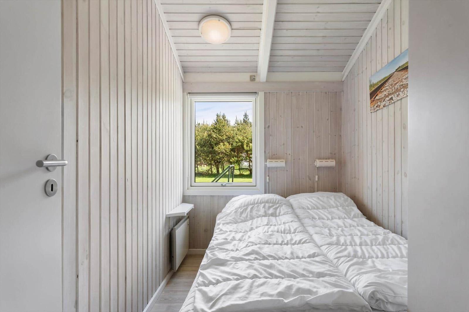 Bedroom with bed, window, and wood paneling.