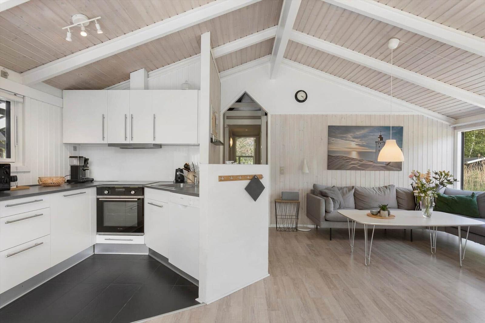 Kitchen with white built-in cabinetry and living area with sofa and table