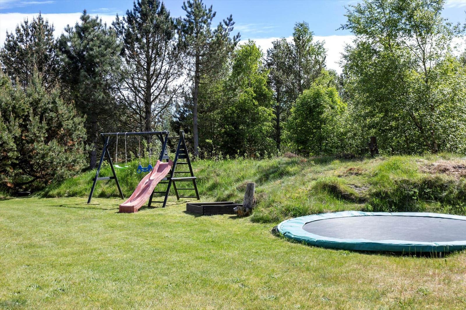 Backyard with trampoline, playground, and lawn.