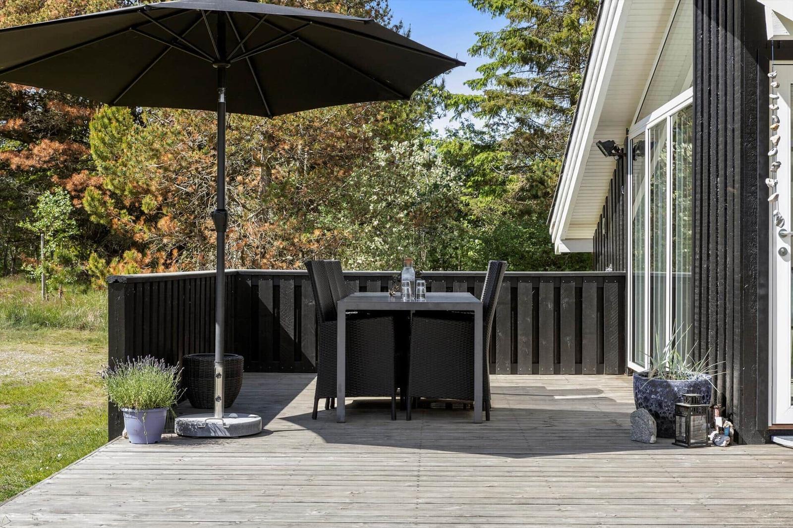 Deck with table, chairs, and umbrella beside house