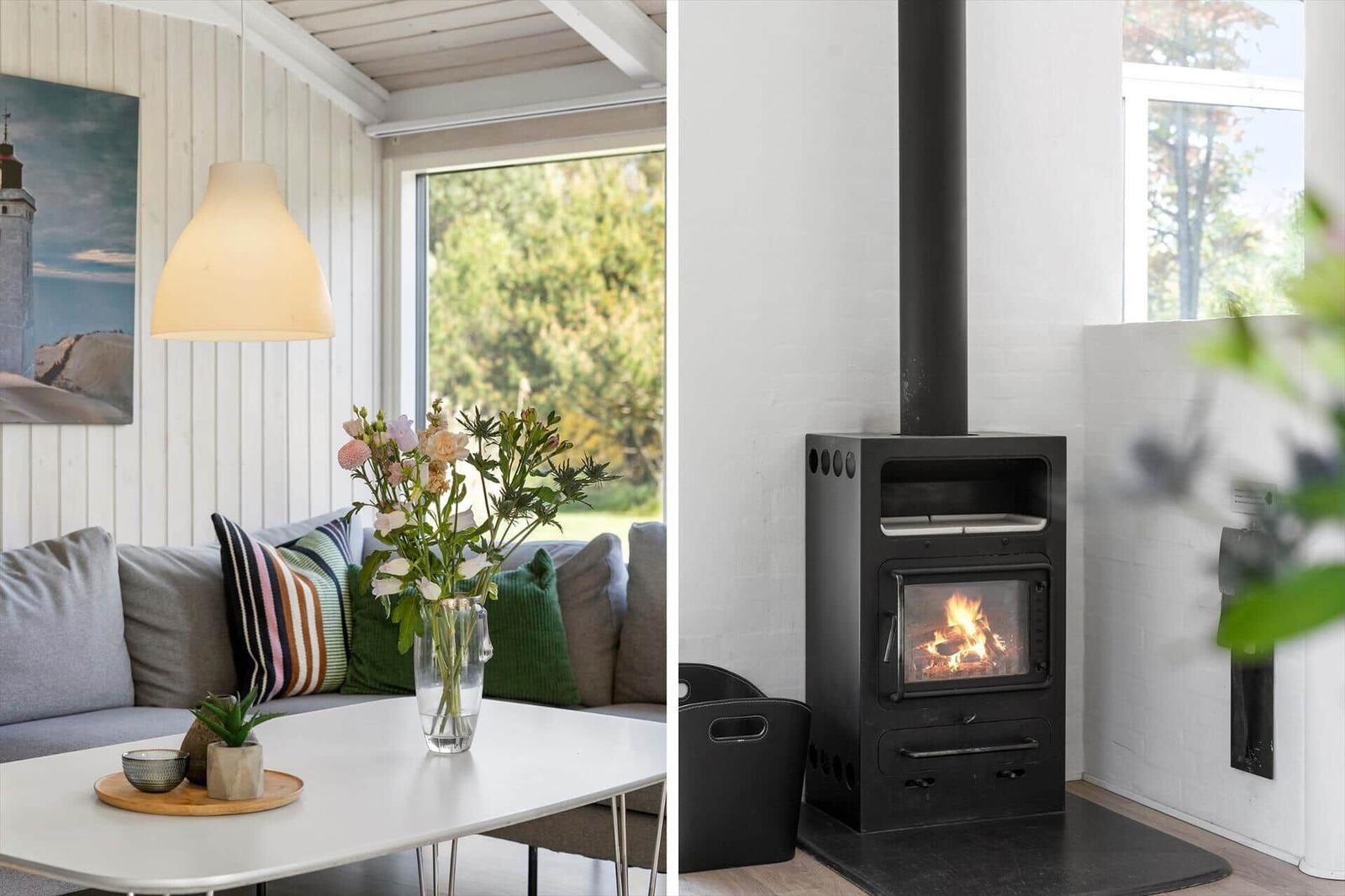 Living room with sofa, table, and flowers. Fireplace with burning wood.