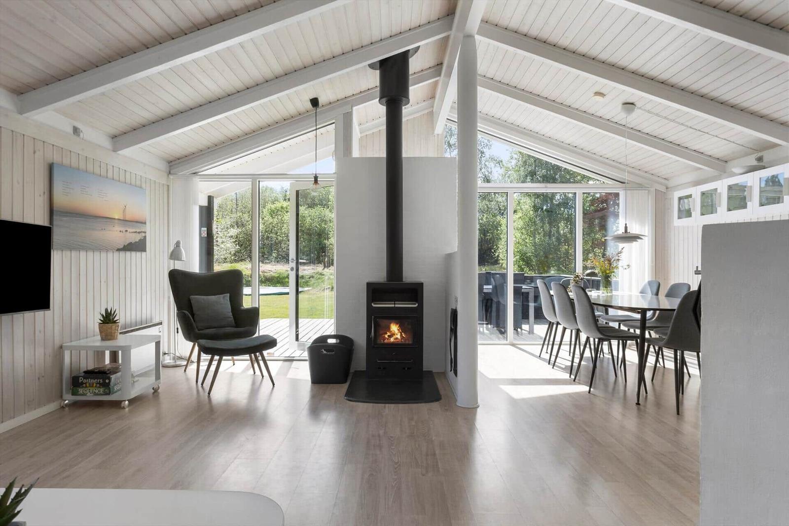 Living and dining area with fireplace, glass doors, and wooden floor.