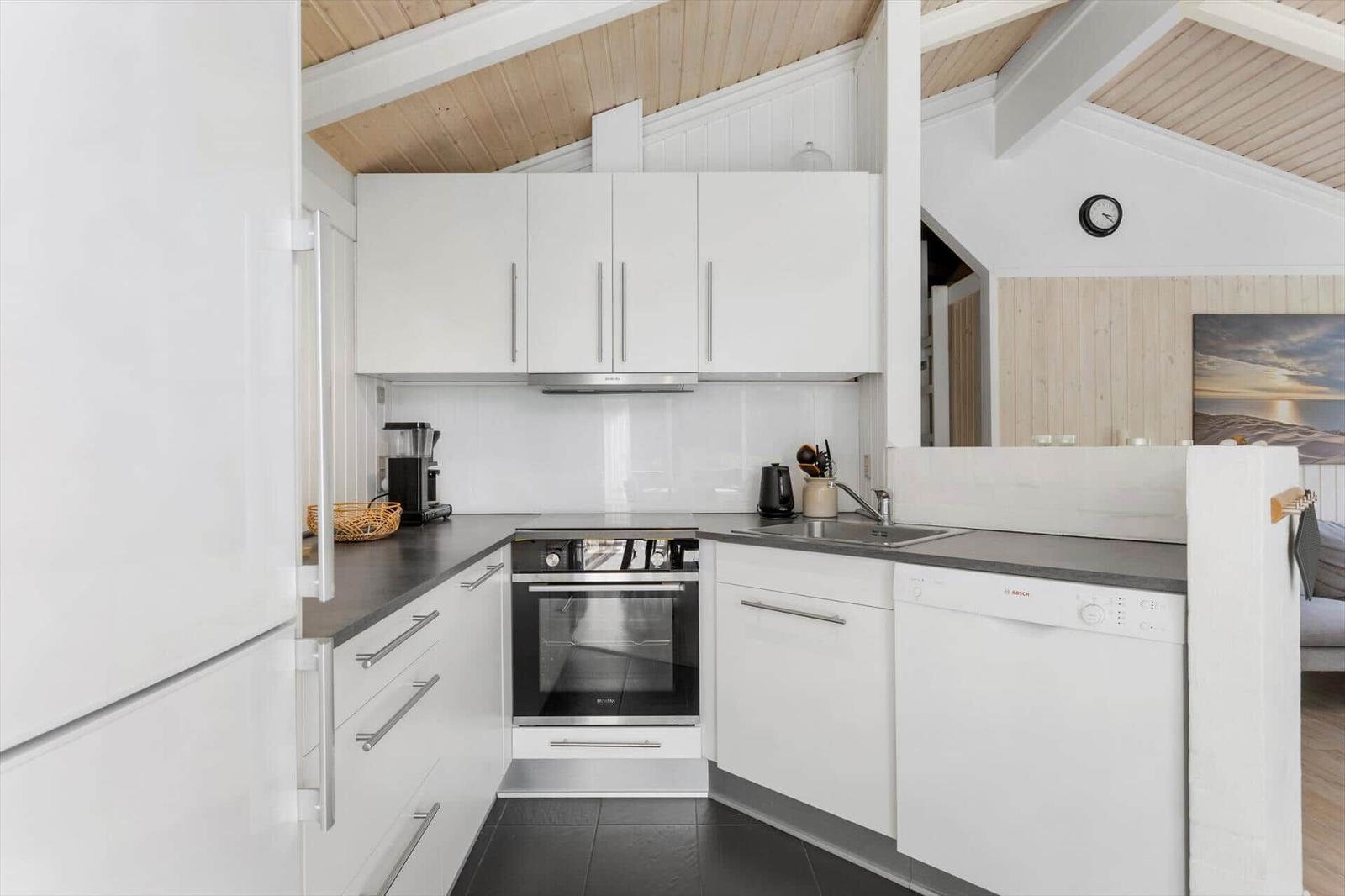 Modern kitchen with white cabinets, stainless steel appliances, and dark countertops.
