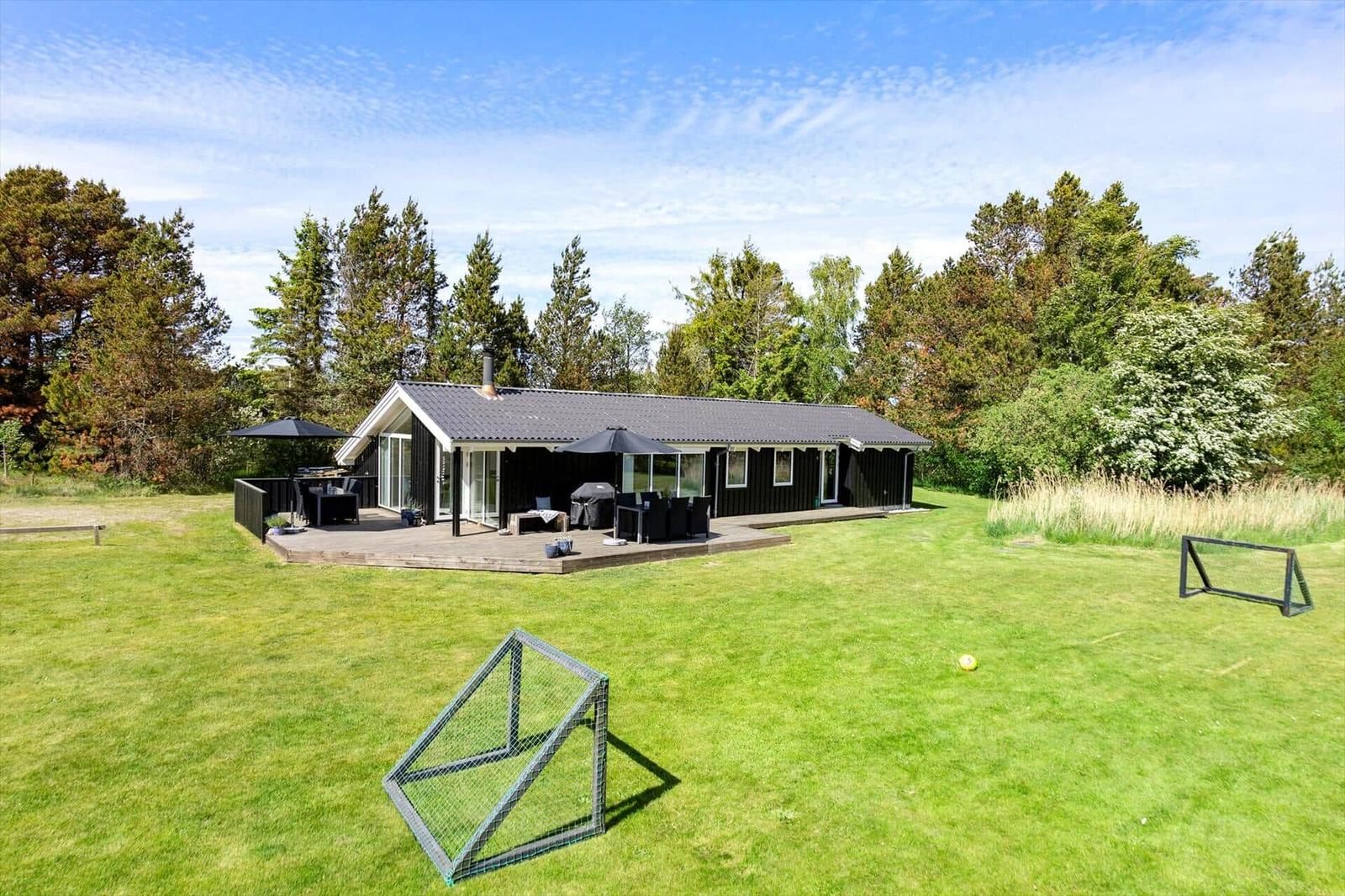 Black house with terrace, lawn, and soccer goals.
