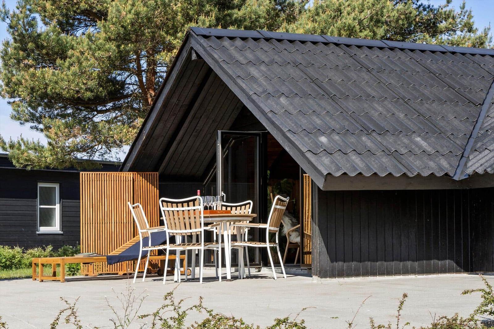 Black wooden house with terrace, table and chairs under a roof