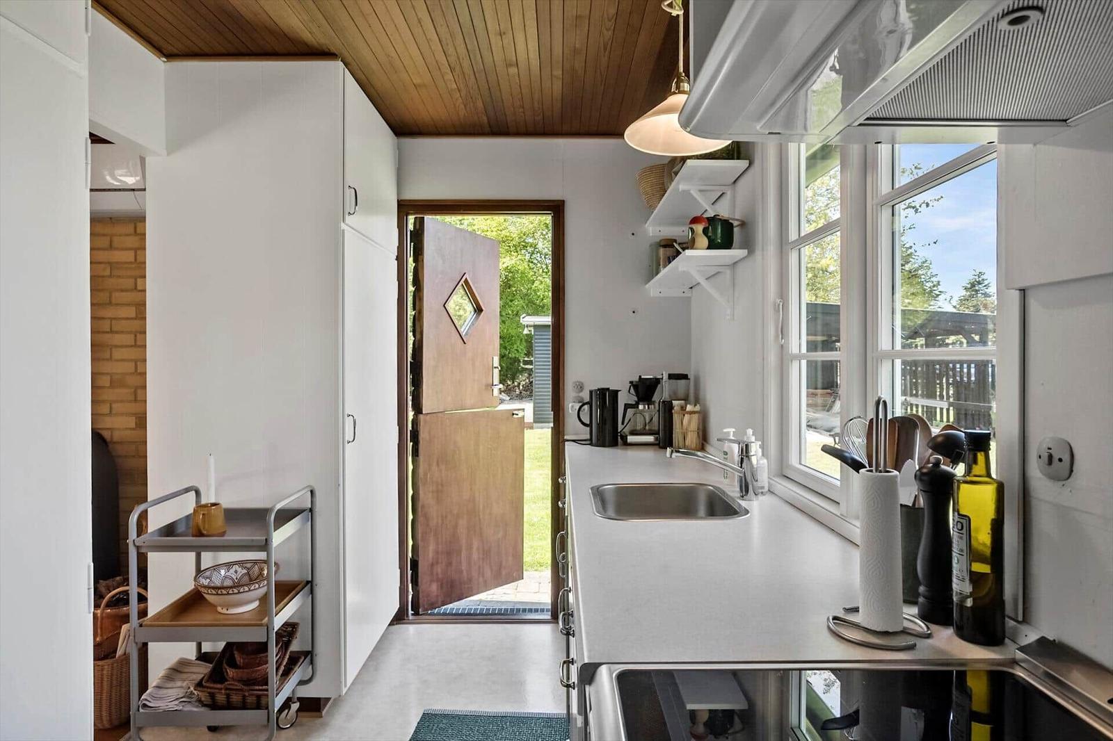 Küche mit Arbeitsfläche, Spüle und Fenster zum Garten.