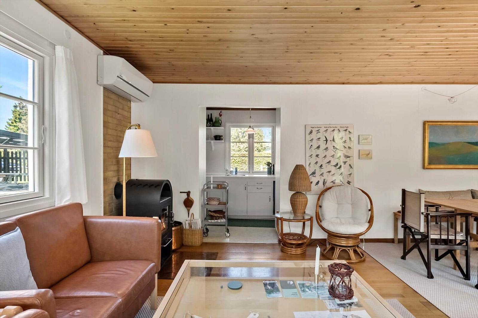 Wohnzimmer mit Holzdecke, Sofa, Esstisch und Küchenbereich.