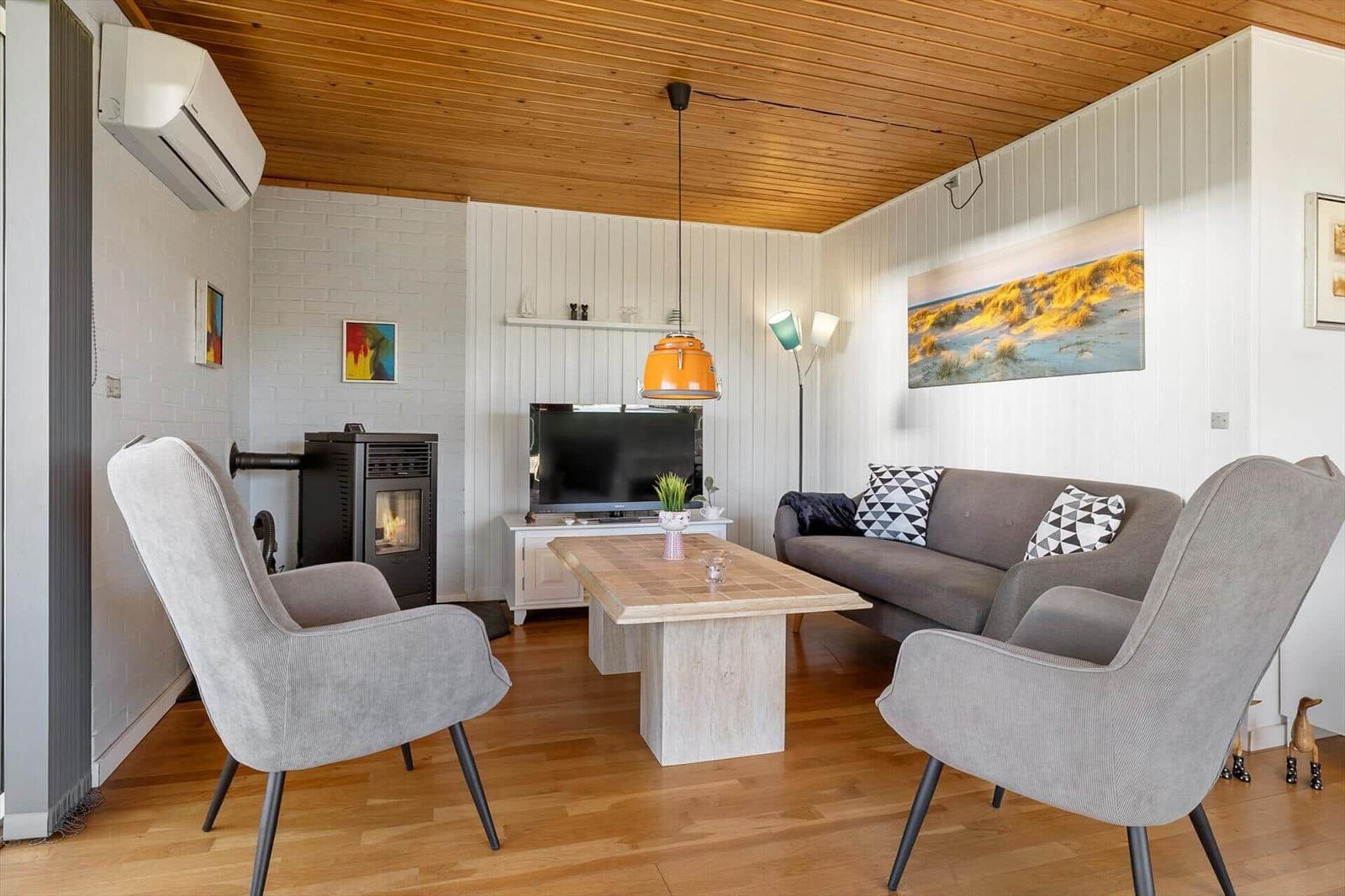 Living room with sofa, two armchairs, fireplace, and TV.