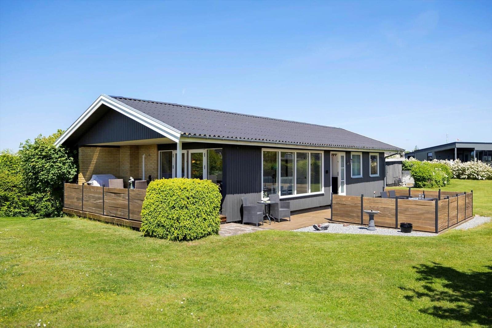 Modern villa with terrace and garden. Grill, seating area, and flower bed.