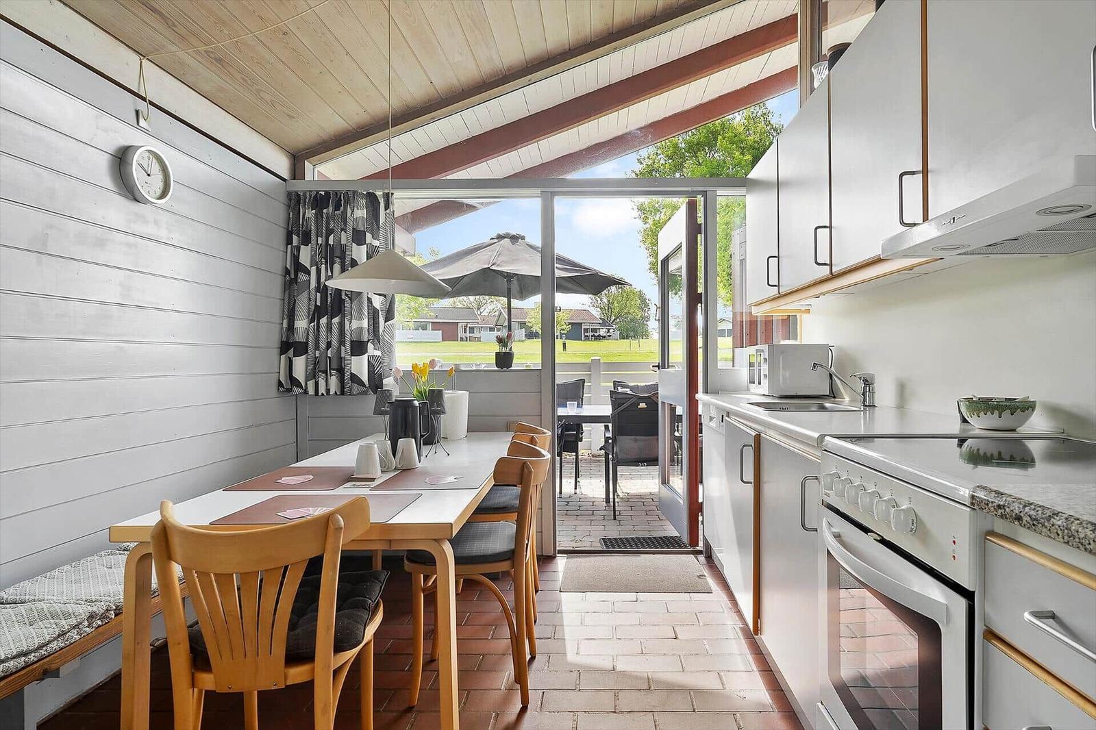 Kitchen with dining table, view to terrace with umbrella.
