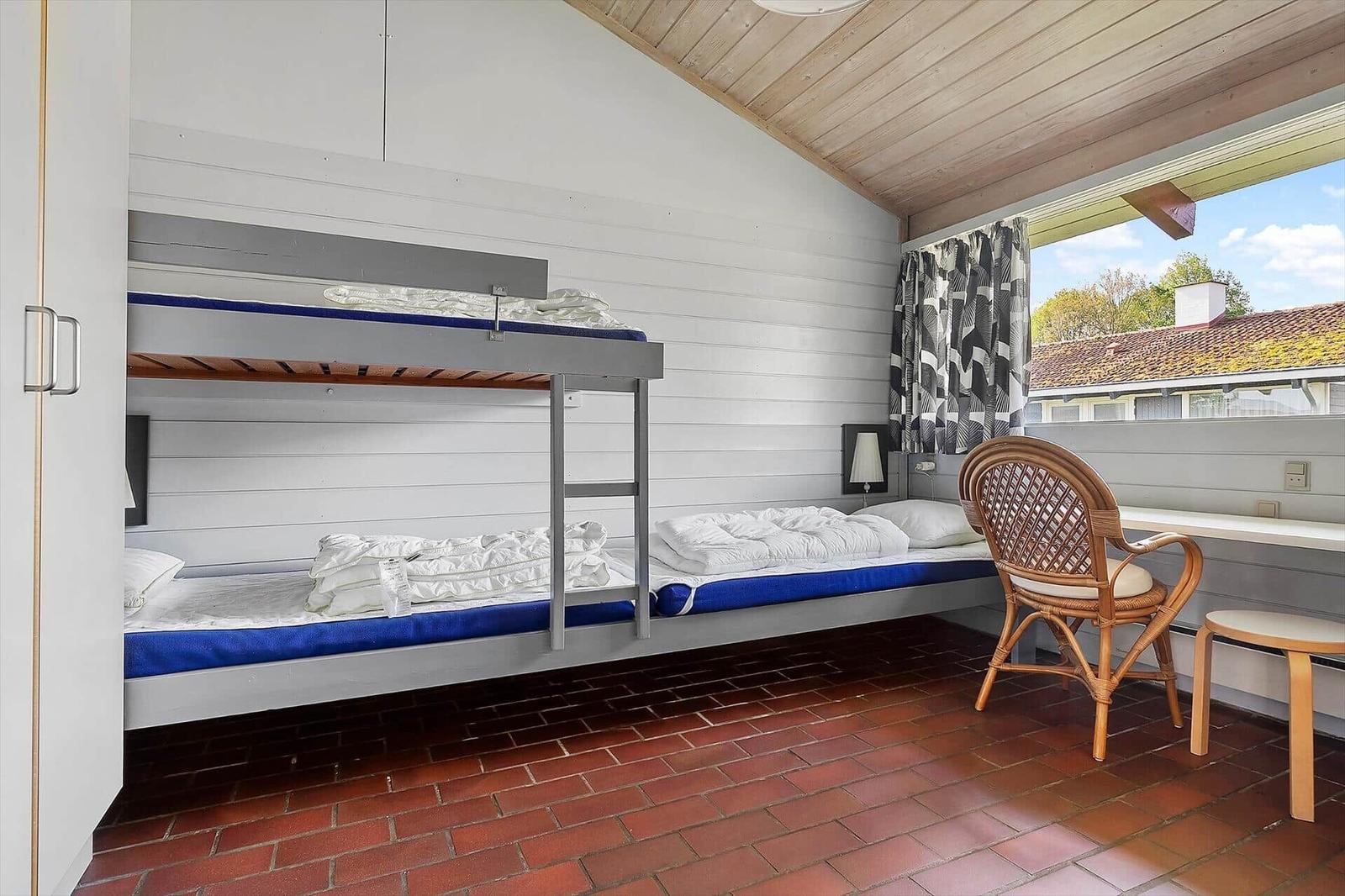 Room with bunk bed, wooden ceiling, and view of outdoor area.