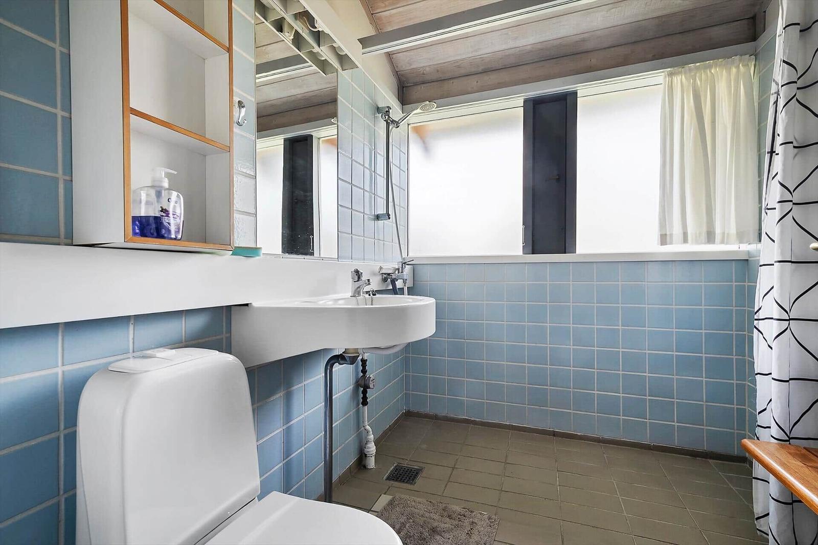 Bathroom with toilet, sink, and shower. Blue tiles on the walls.