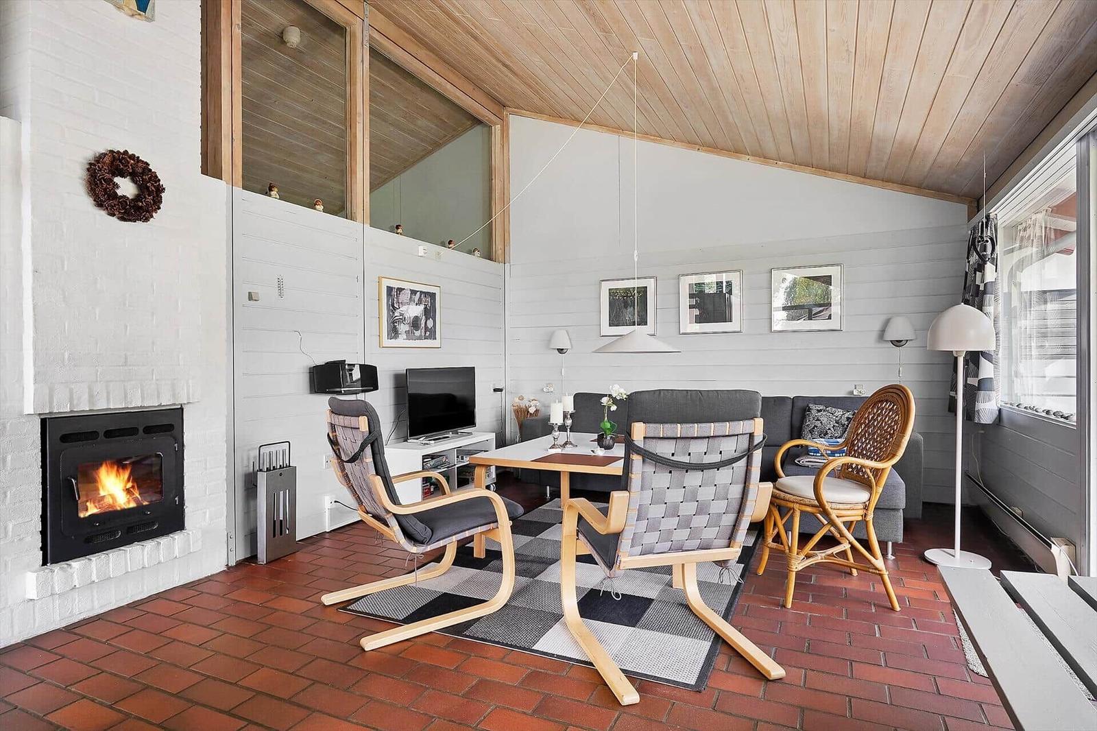 Living room with fireplace, seating area, and dining space on terracotta floor.