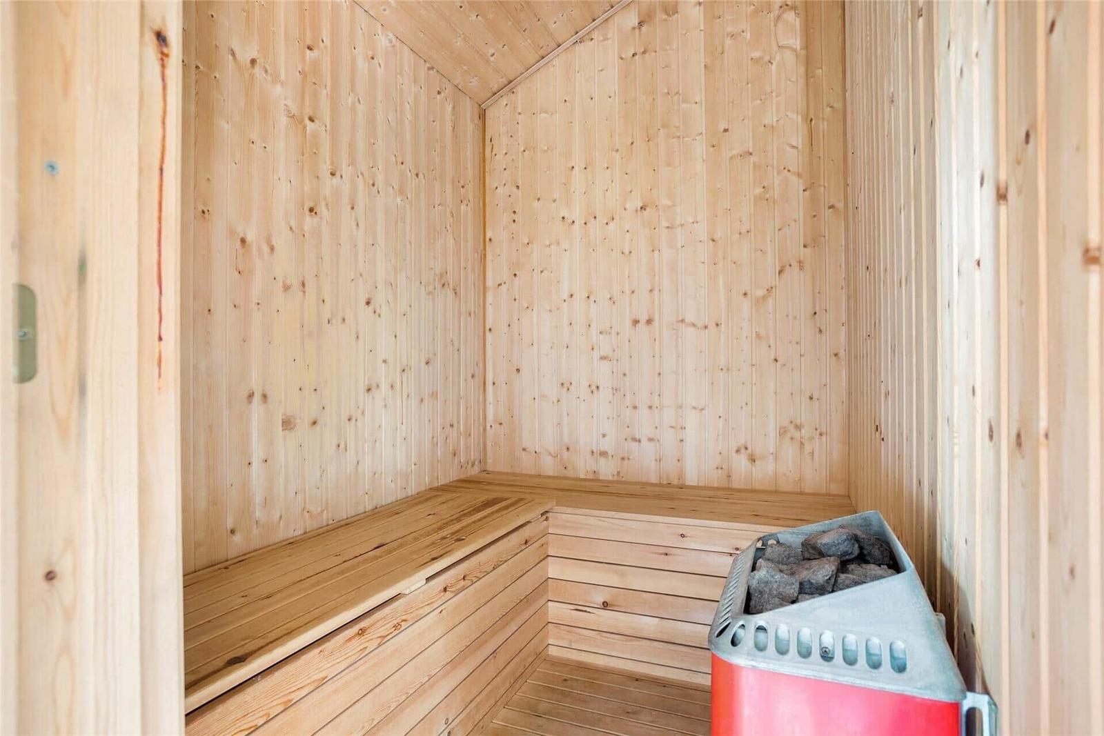 Sauna mit Holzwand und Sitzbank, Heizung mit Steinbecken.