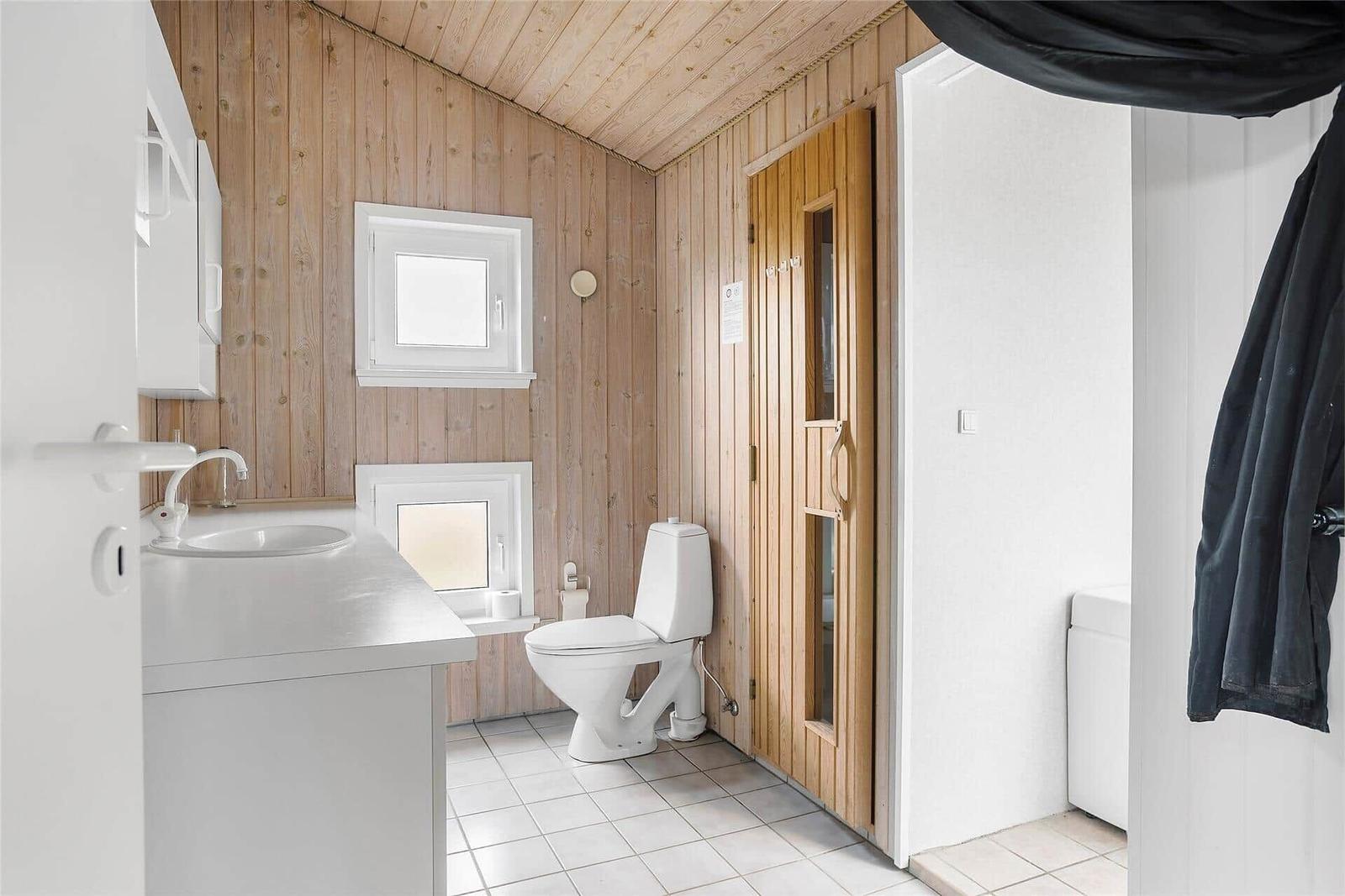 Bad mit Toilette, Waschbecken und Holzwandverkleidung.