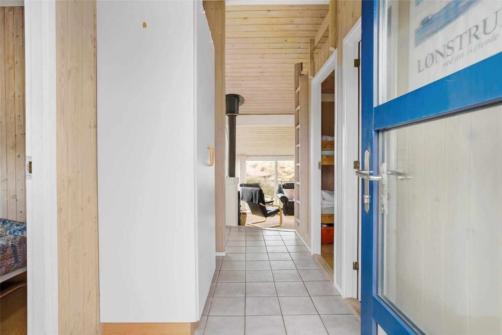Flur mit Holzwänden, gefliestem Boden und Blick in Wohn- und Schlafzimmer.