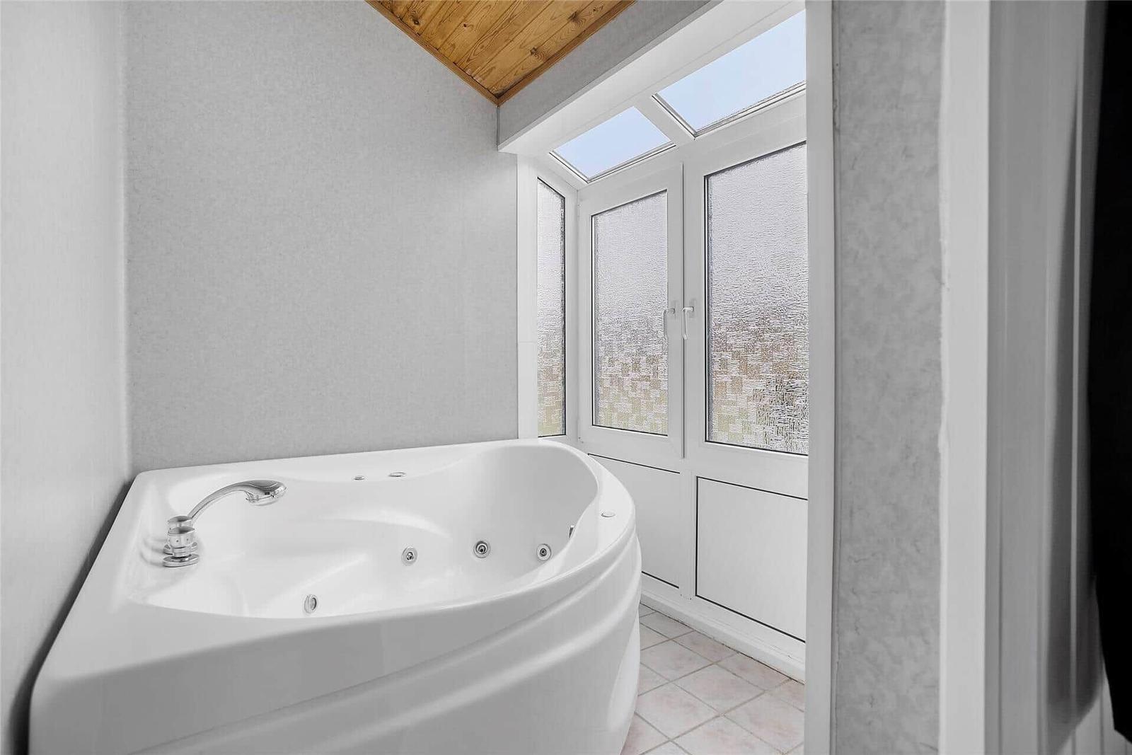 Dusche mit Whirlpool, Fenster mit getöntem Glas und Holzdecke.