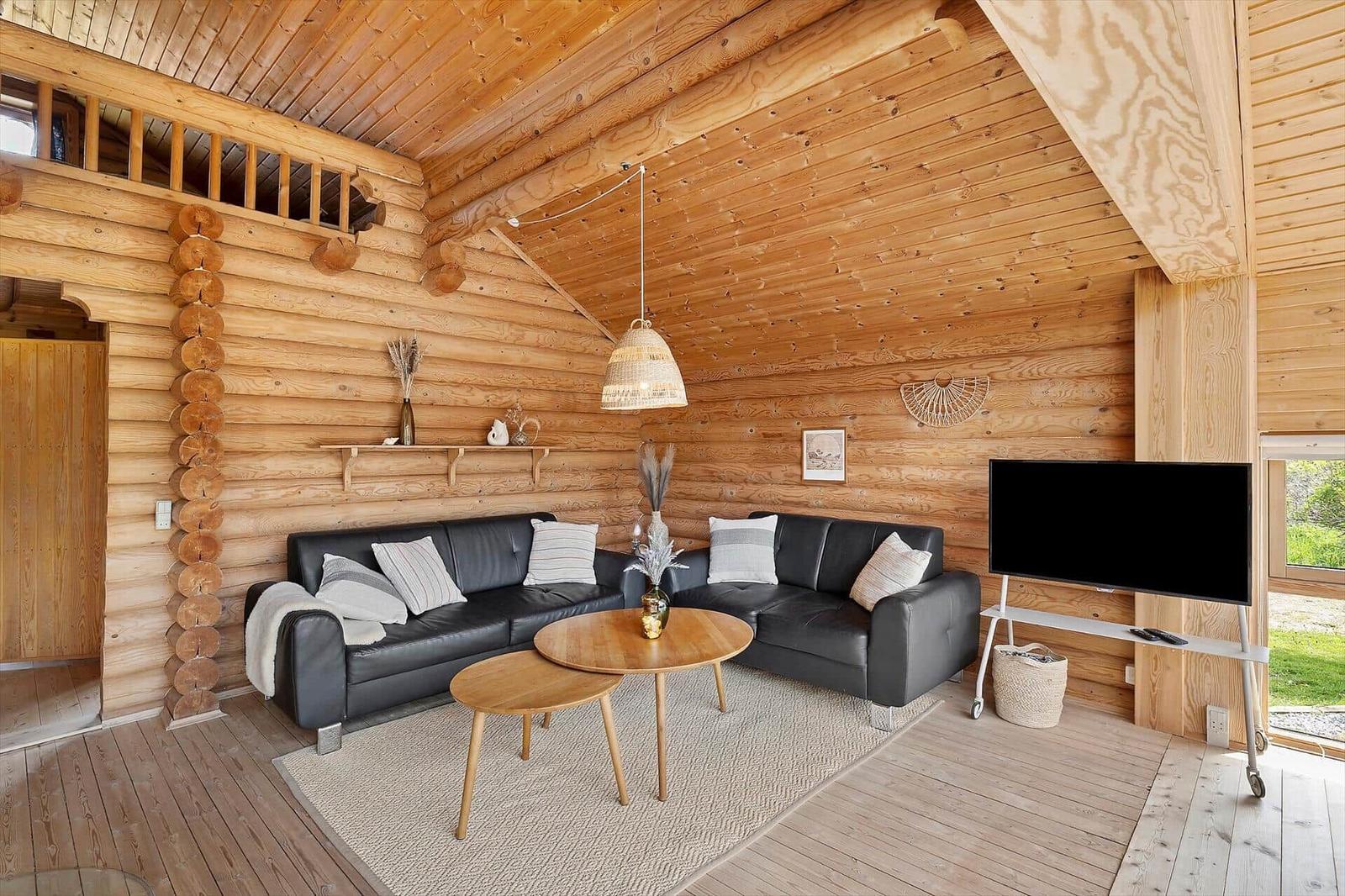 Wohnzimmer mit Holzwand, Sofa, Tisch und Fernseher