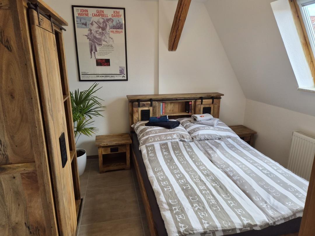 Schlafzimmer mit Doppelbett, Holzmöbel und Dachfenster.