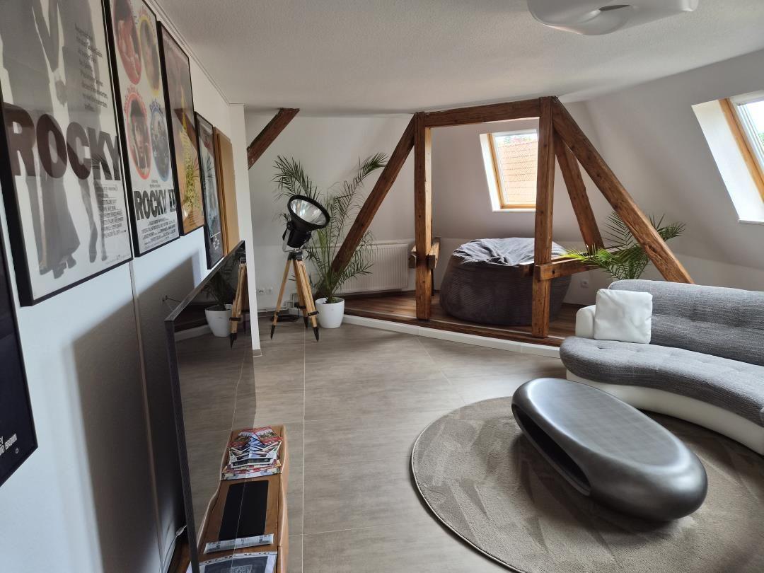 Wohnraum mit Sofa, Beistelltisch und Filmplakaten an der Wand.