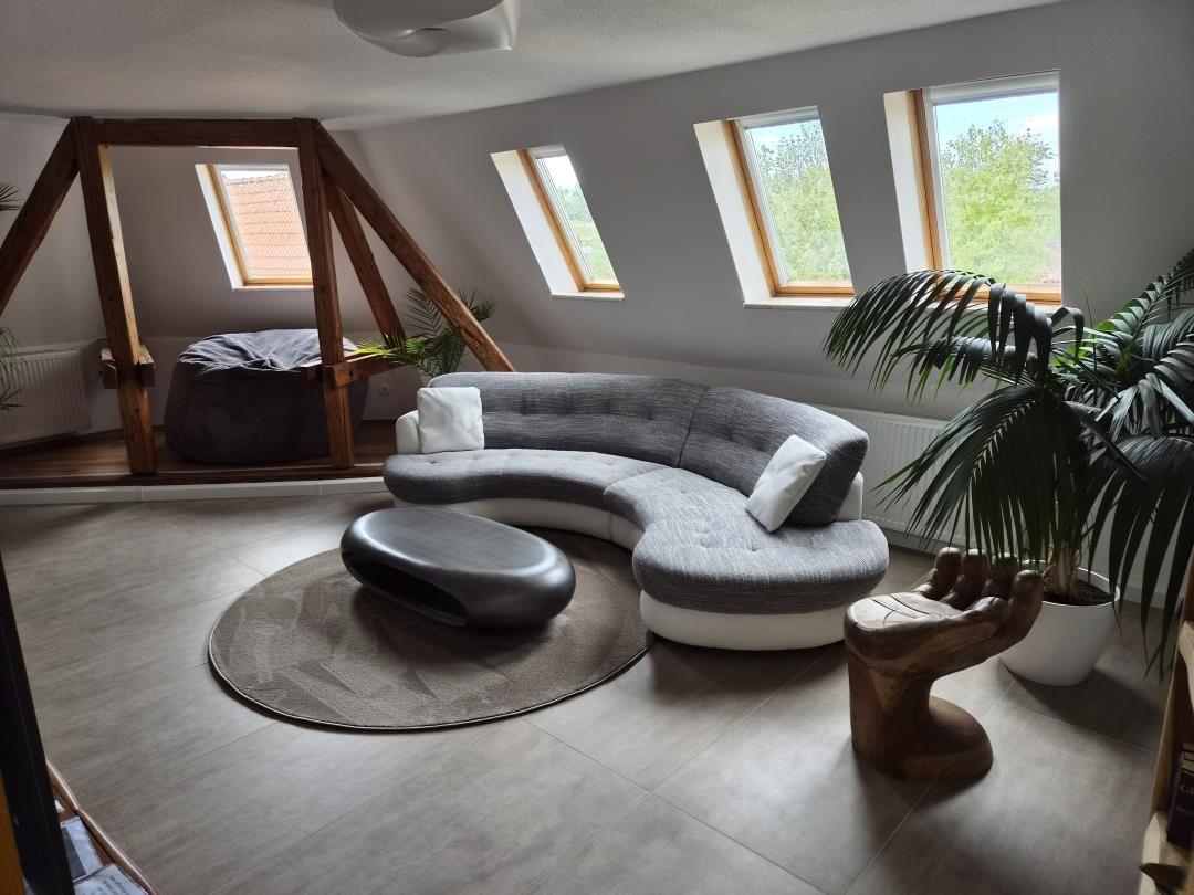 Dachgeschosswohnung mit Sitzbereich, Fenstern und Pflanzen.