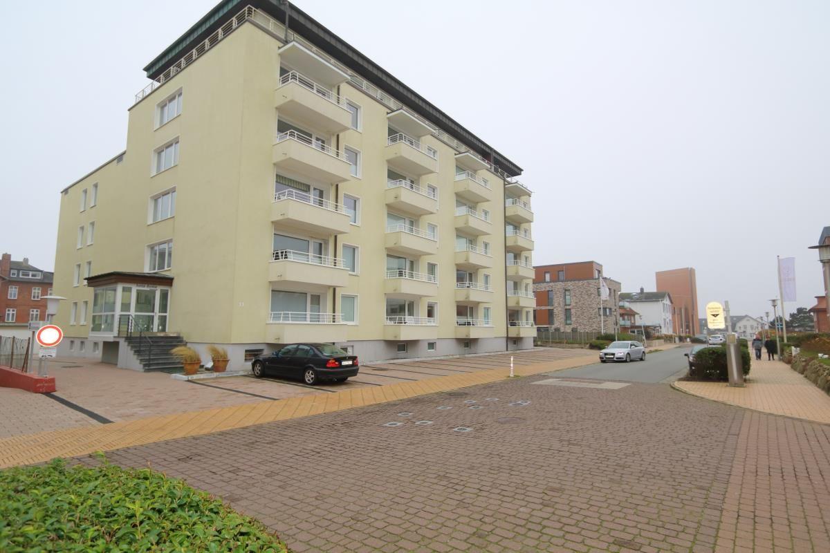 Five-story residential building with balconies and parking lot.