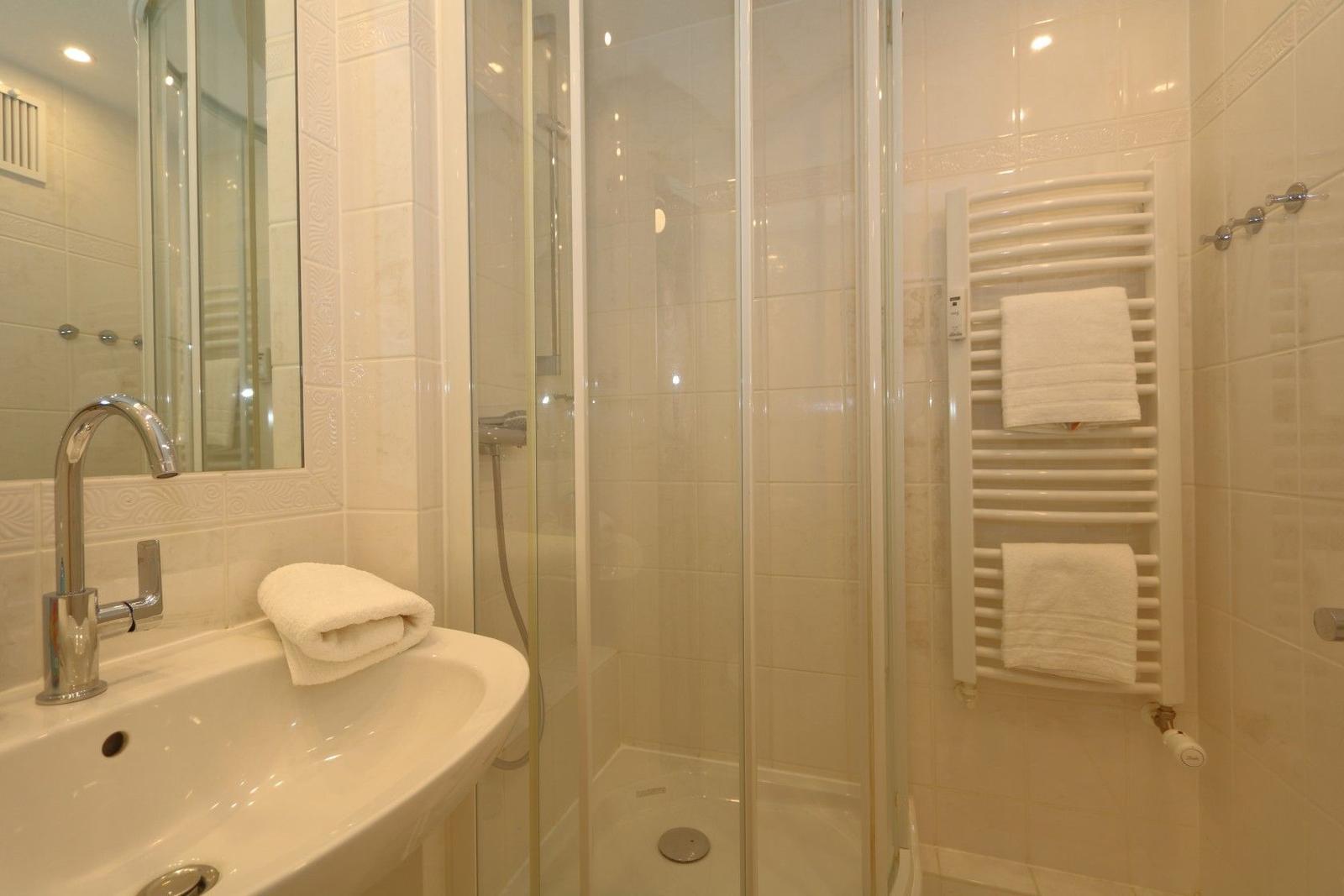Bathroom with shower, sink, and towel rack.
