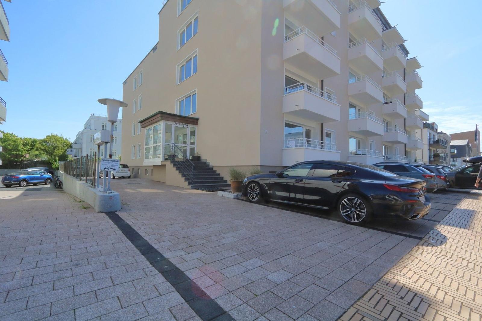 Modern apartment with balcony, parking space, and entrance area. Building with multiple floors.