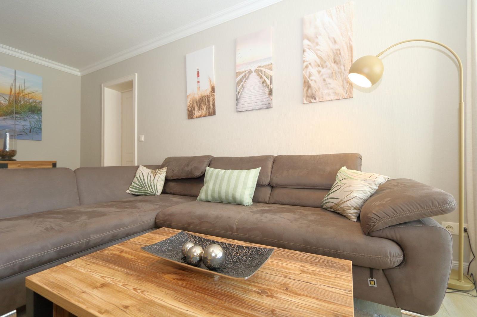 A living room with brown sofa, wooden table, and wall art.