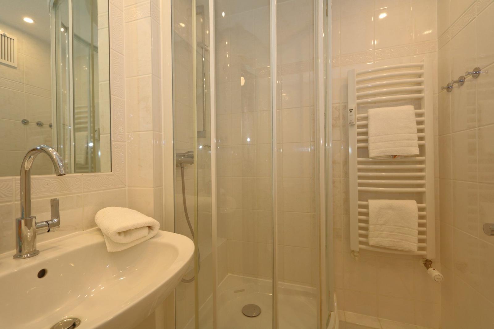 Bathroom with shower, sink, and towel rack.