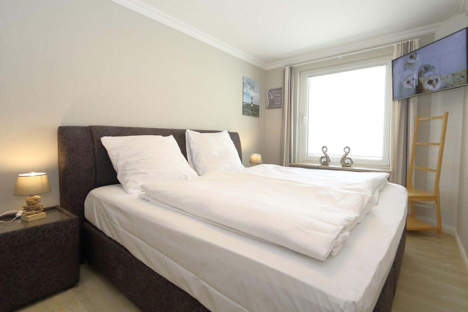 Bedroom with double bed, window, TV and bedside table.