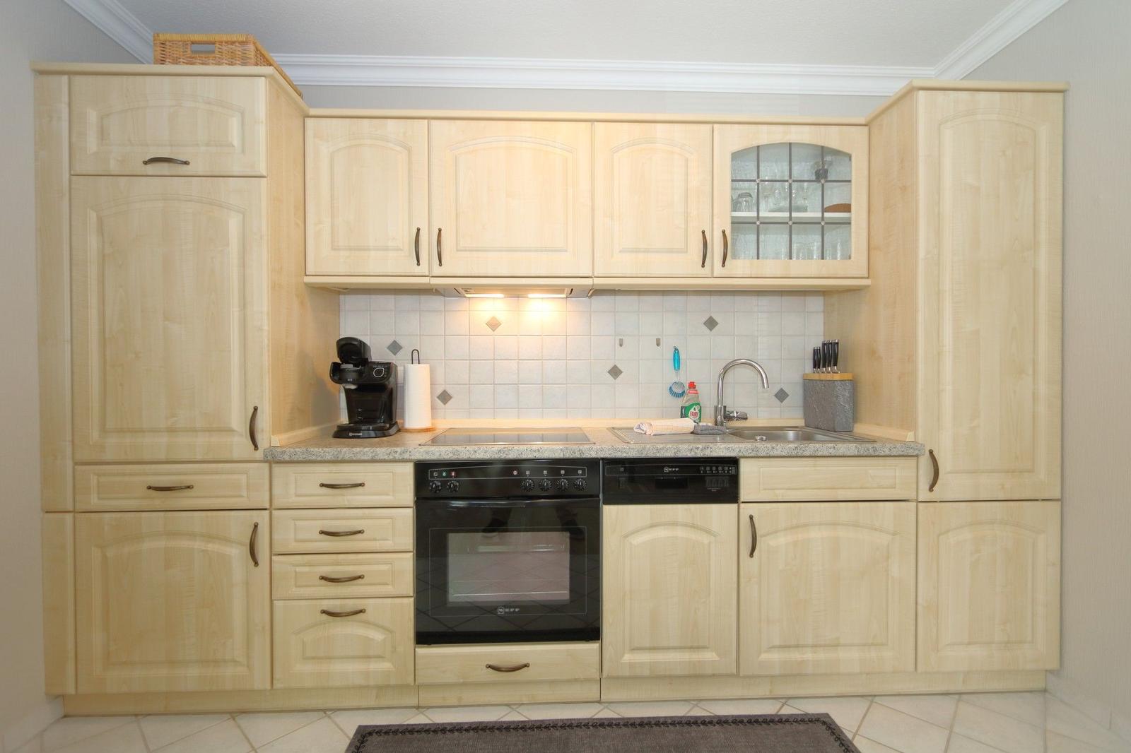 Kitchen with light cabinets, sink, stove, and refrigerator.