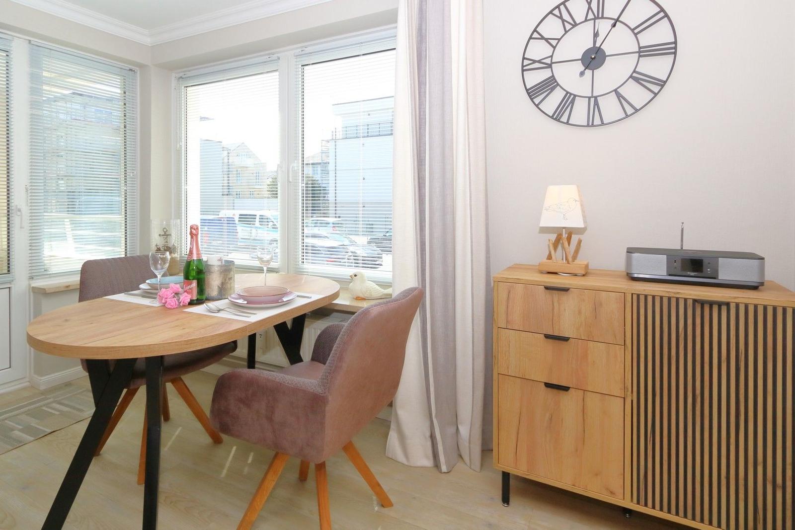 Dining table with chairs, cabinet, and wall clock in dining area.