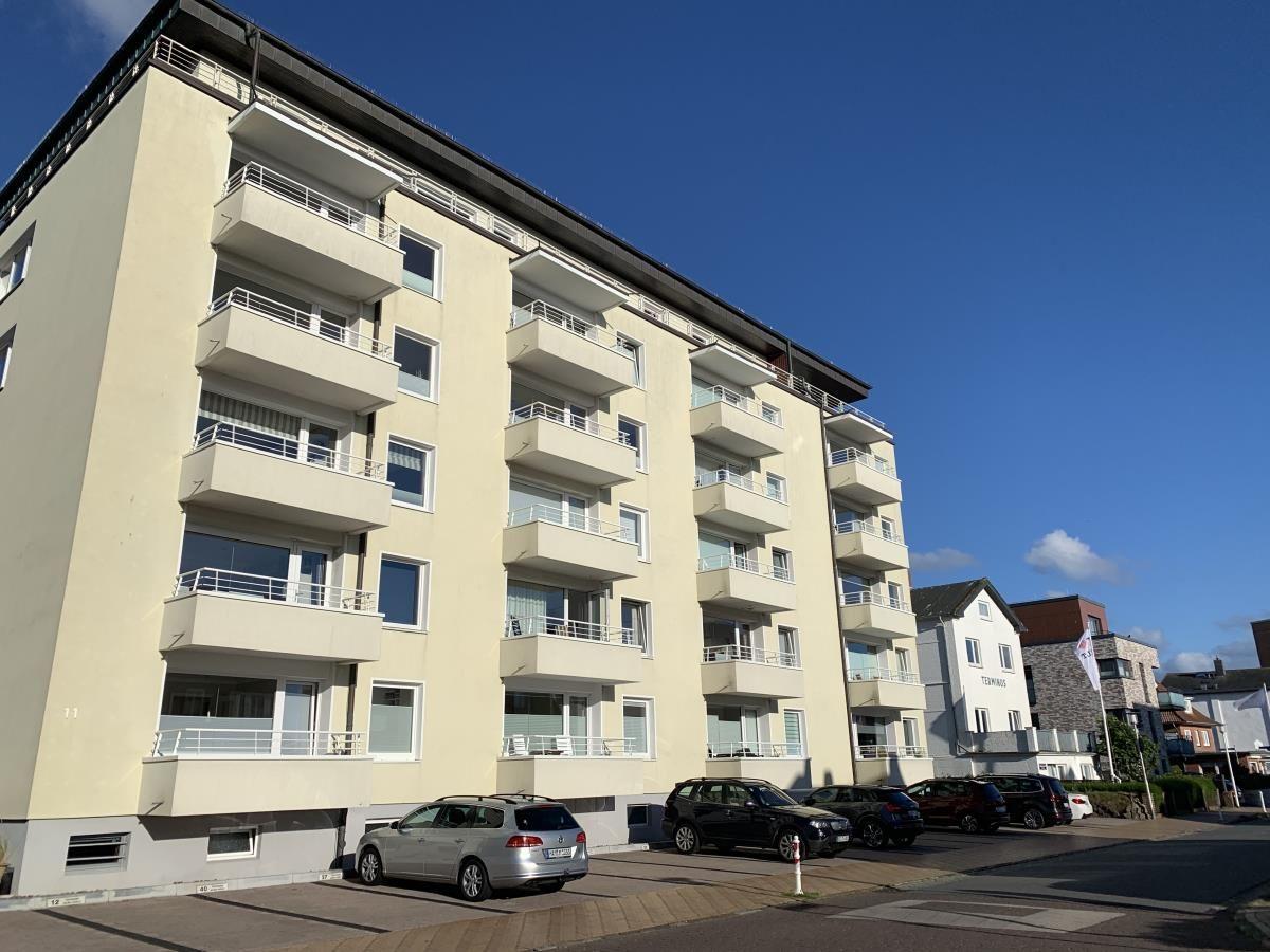 Multi-family building with balconies and parking spaces under blue sky