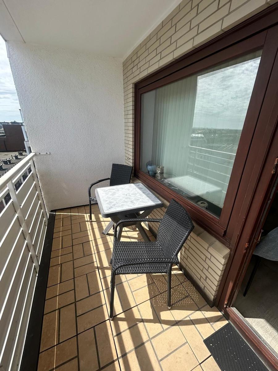 Terrasse mit Tisch und zwei Stühlen, Blick auf die Stadt.
