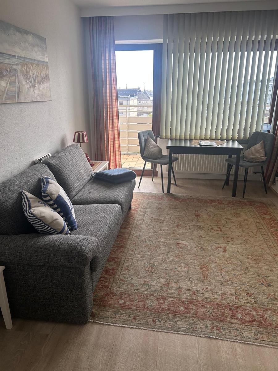 Wohnzimmer mit Sofa, Tisch und Stühlen, Blick auf Balkon mit Blick auf Stadt.