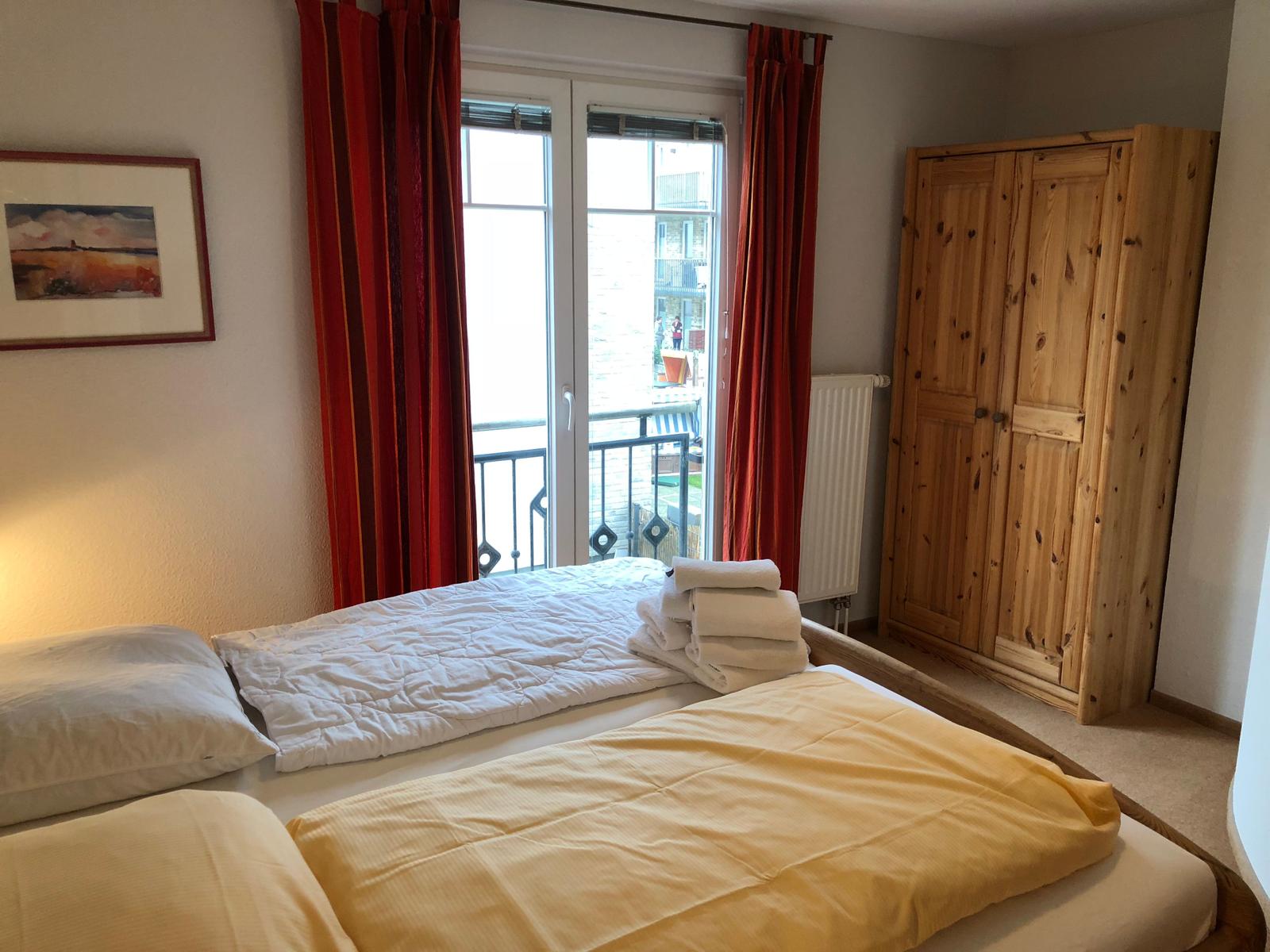 Schlafzimmer mit Doppelbett, Holzschrank und Balkon mit Blick.