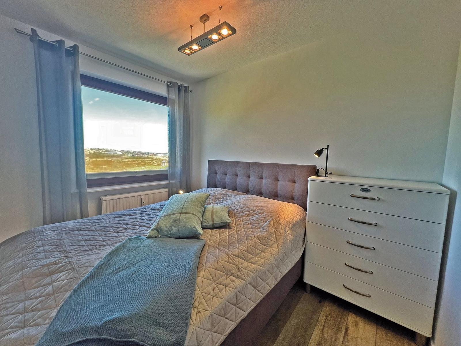 Schlafzimmer mit Bett, Schrank und Fensterblick