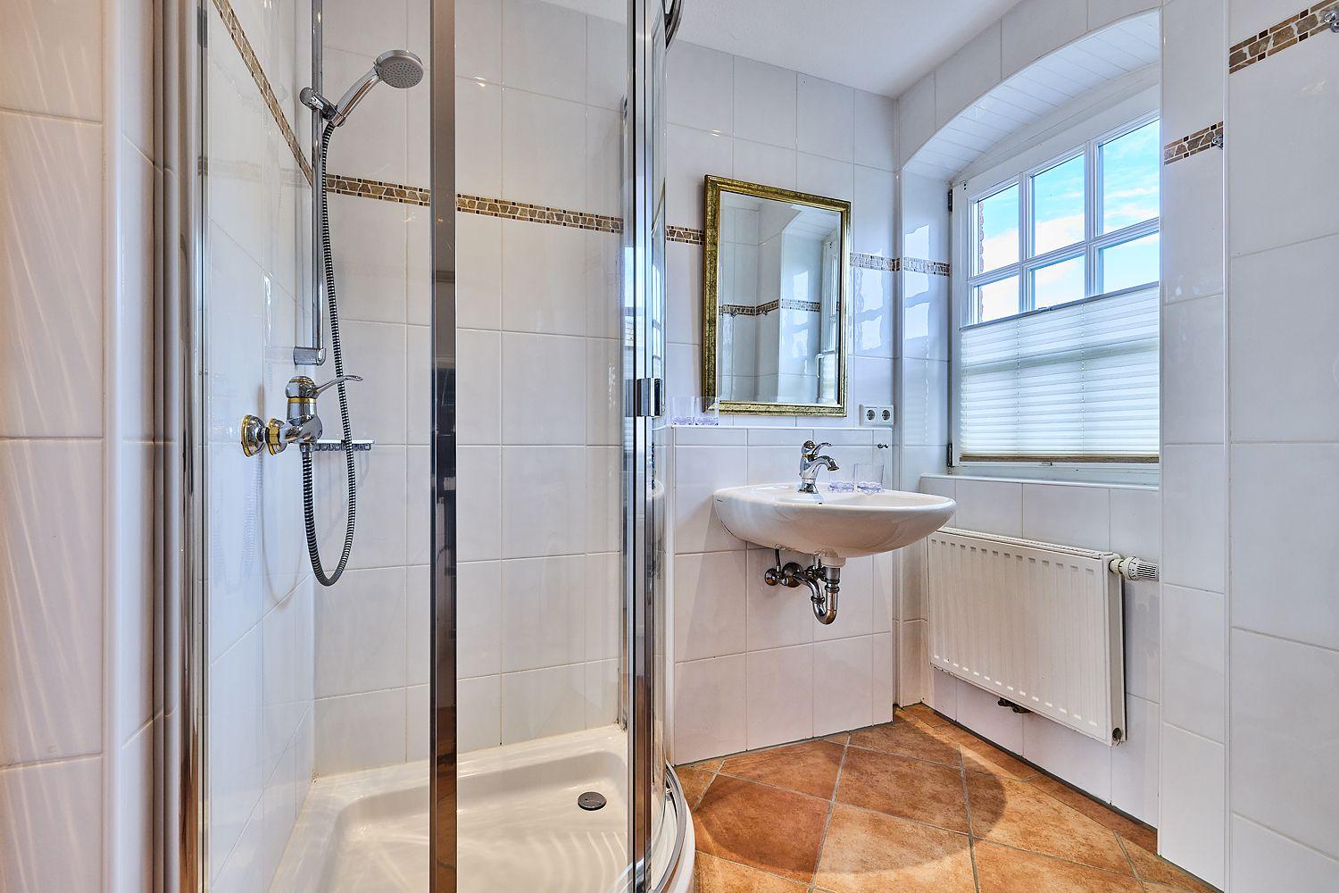 Bad mit Dusche, Waschbecken und Fenster.