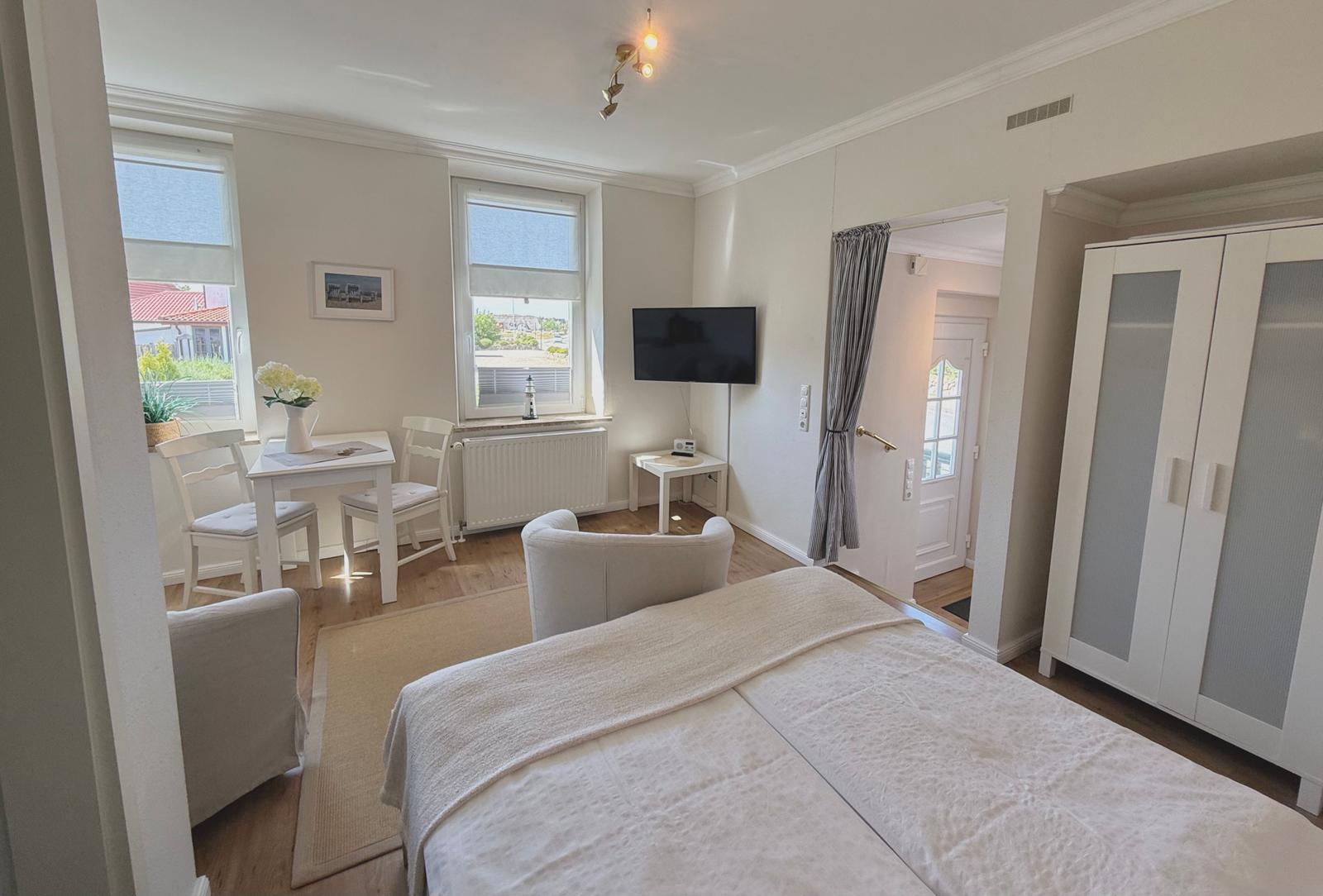 Schlafzimmer mit Bett, TV, Schrank und Essbereich mit Tisch und Stühlen.
