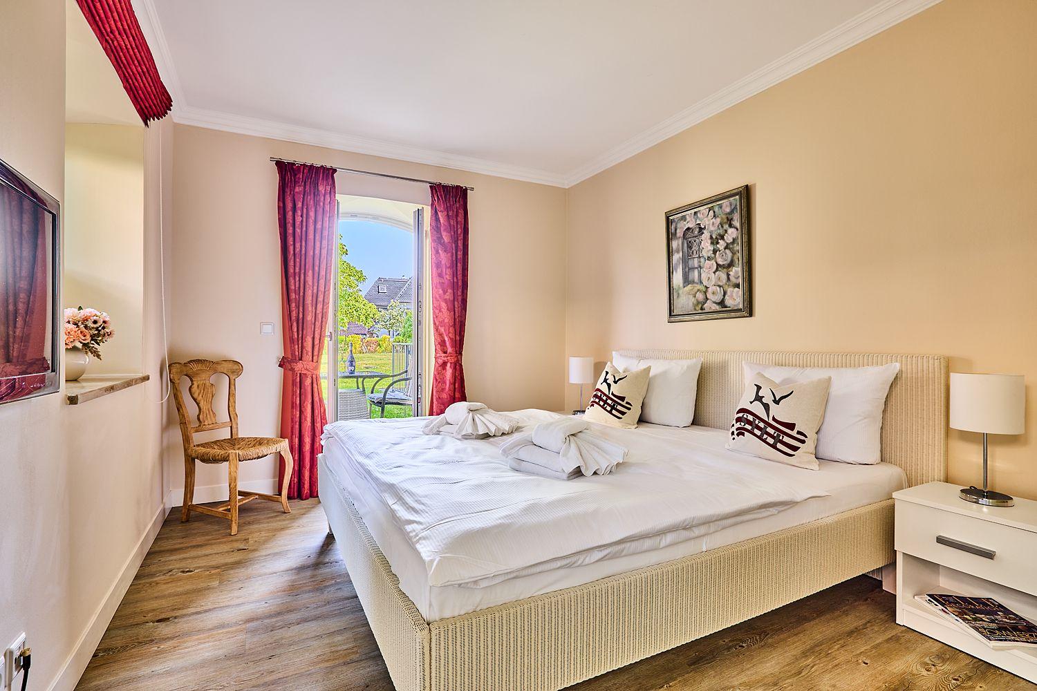 Schlafzimmer mit Bett, Nachttischen und Blick auf Garten