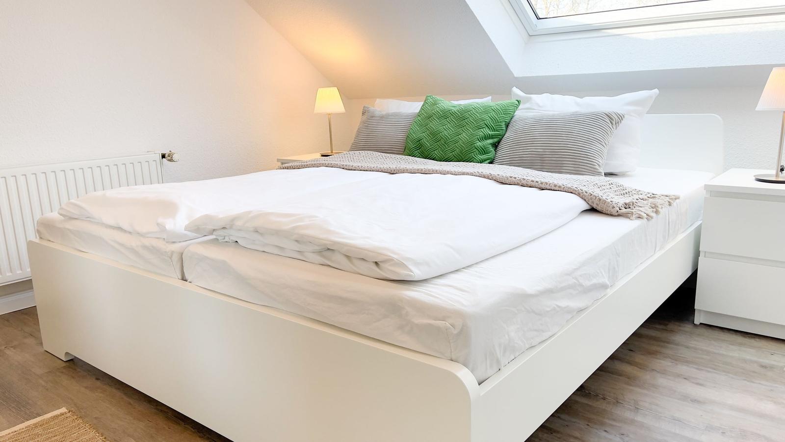 Schlafzimmer mit Doppelbett, Nachttischen und Dachfenster.
